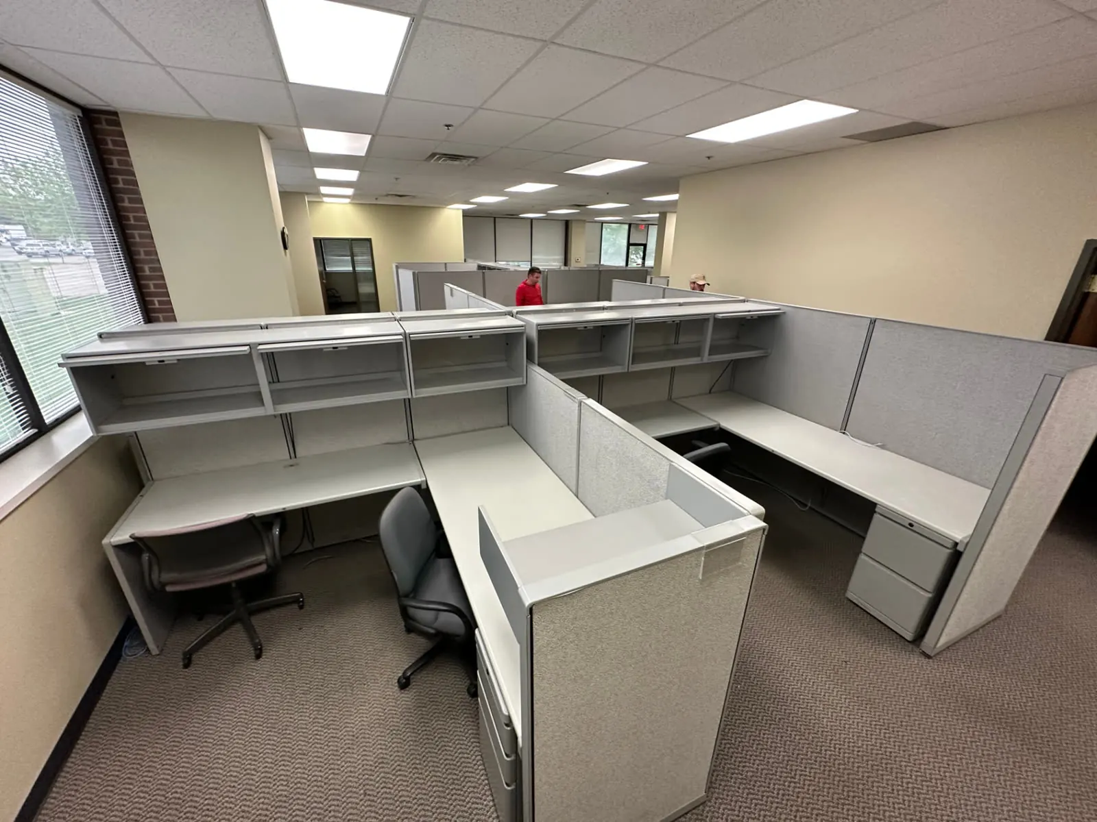 Cubicle pods with desks, shelving, and chairs staged for haul-away