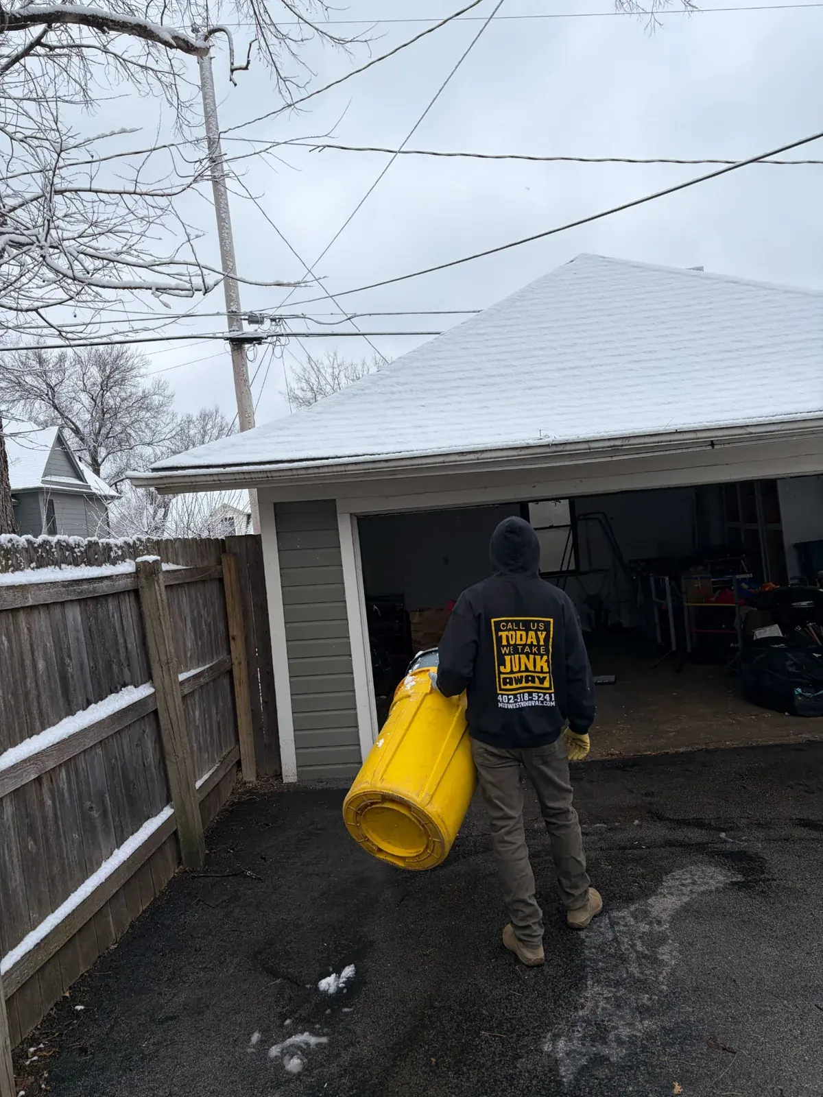 Crew member carrying a bin out of a garage on a snowy Omaha morning