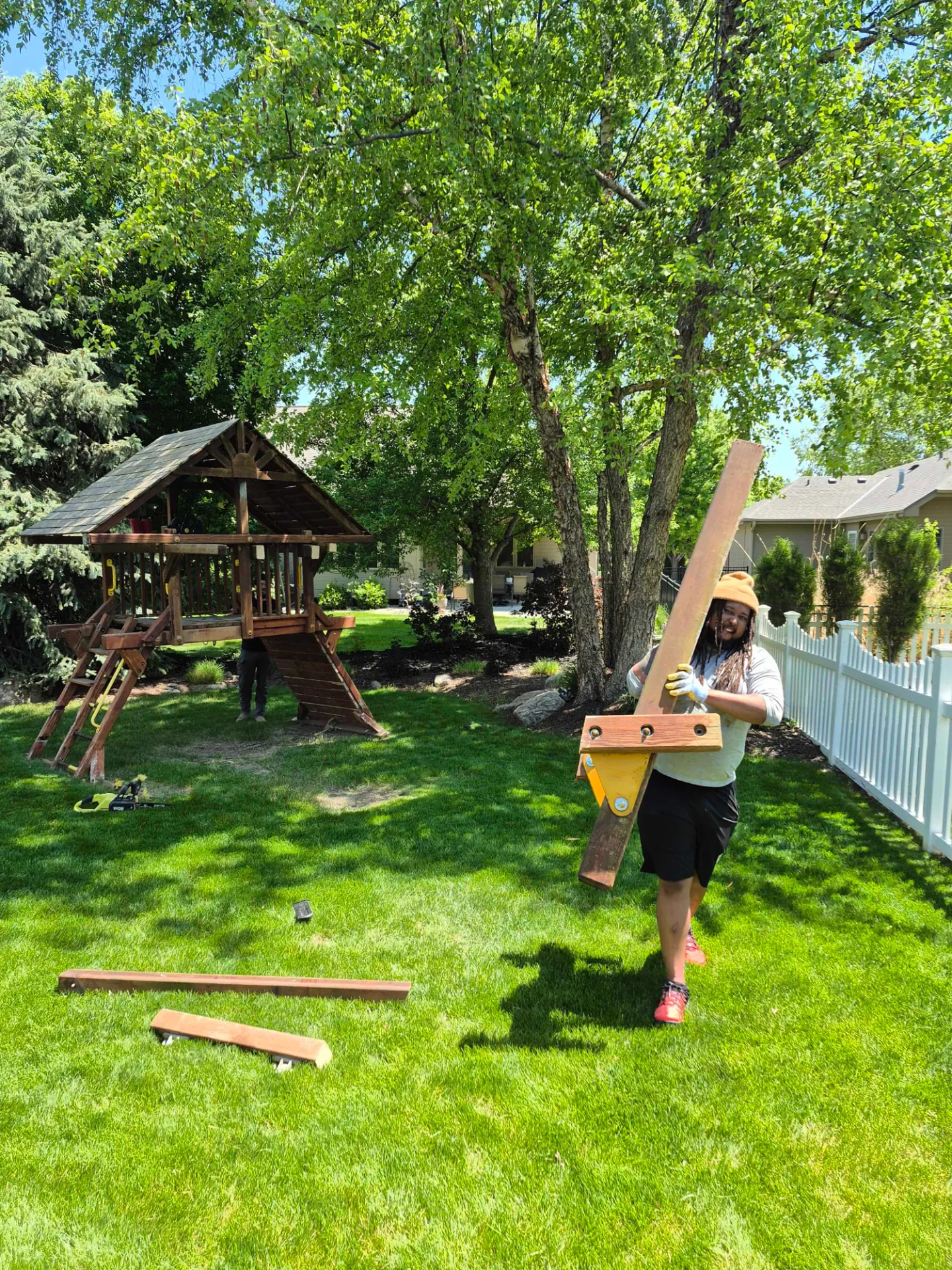 Crew carrying playset beams out of the backyard, Omaha