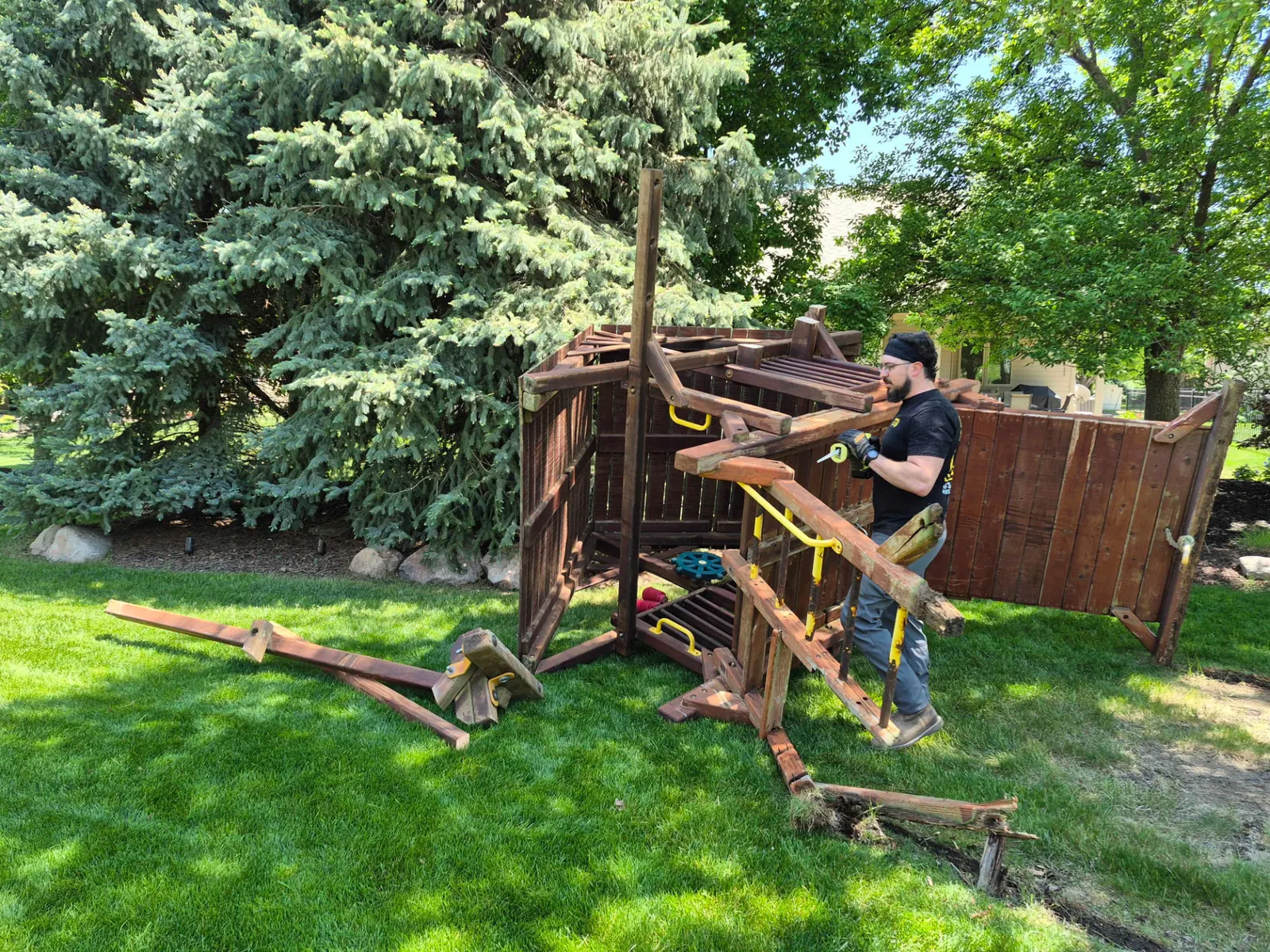 Midwest Removal crew member dismantling a wooden backyard playset in Omaha