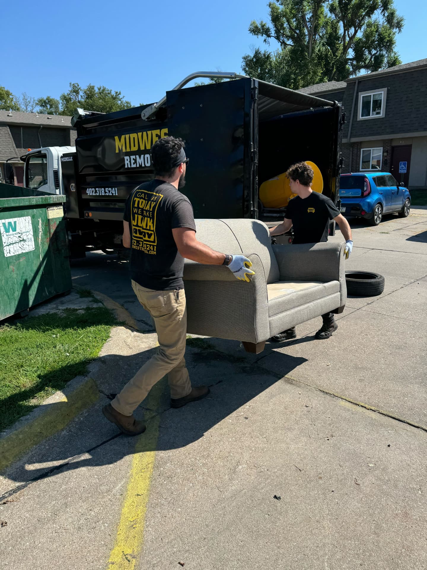 Two Midwest Removal crew members carrying a couch to the truck in Papillion