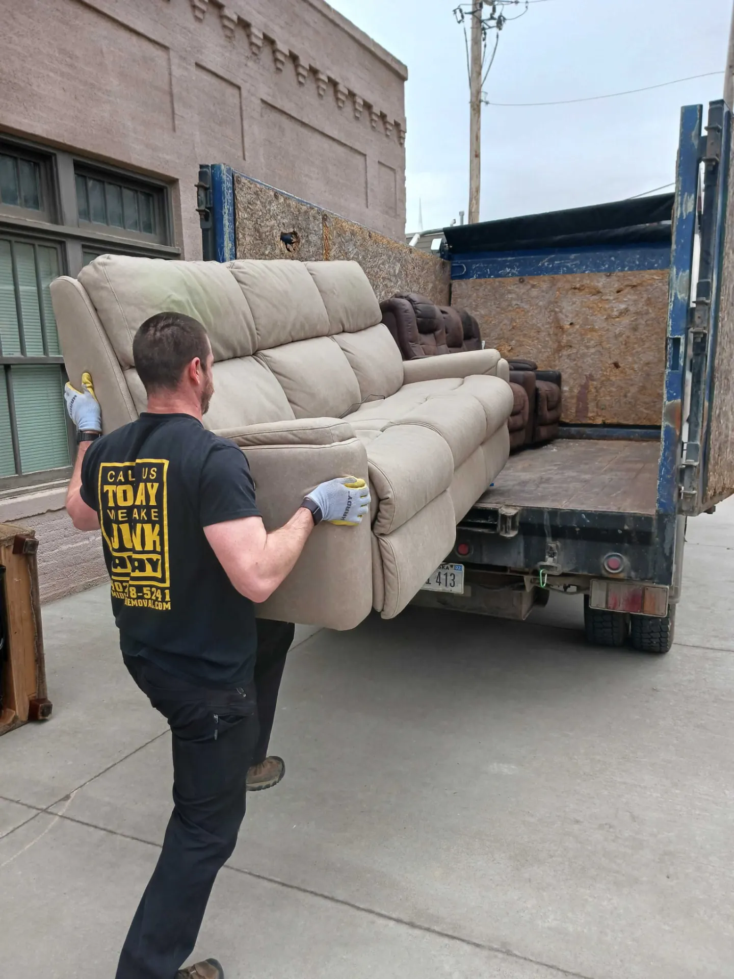 Midwest Removal crew member carrying a couch into the company dump truck in Bellevue