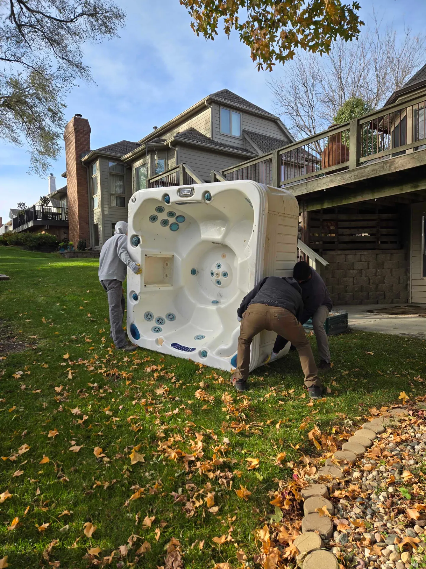 Two crew members hauling a hot tub across a Blair backyard