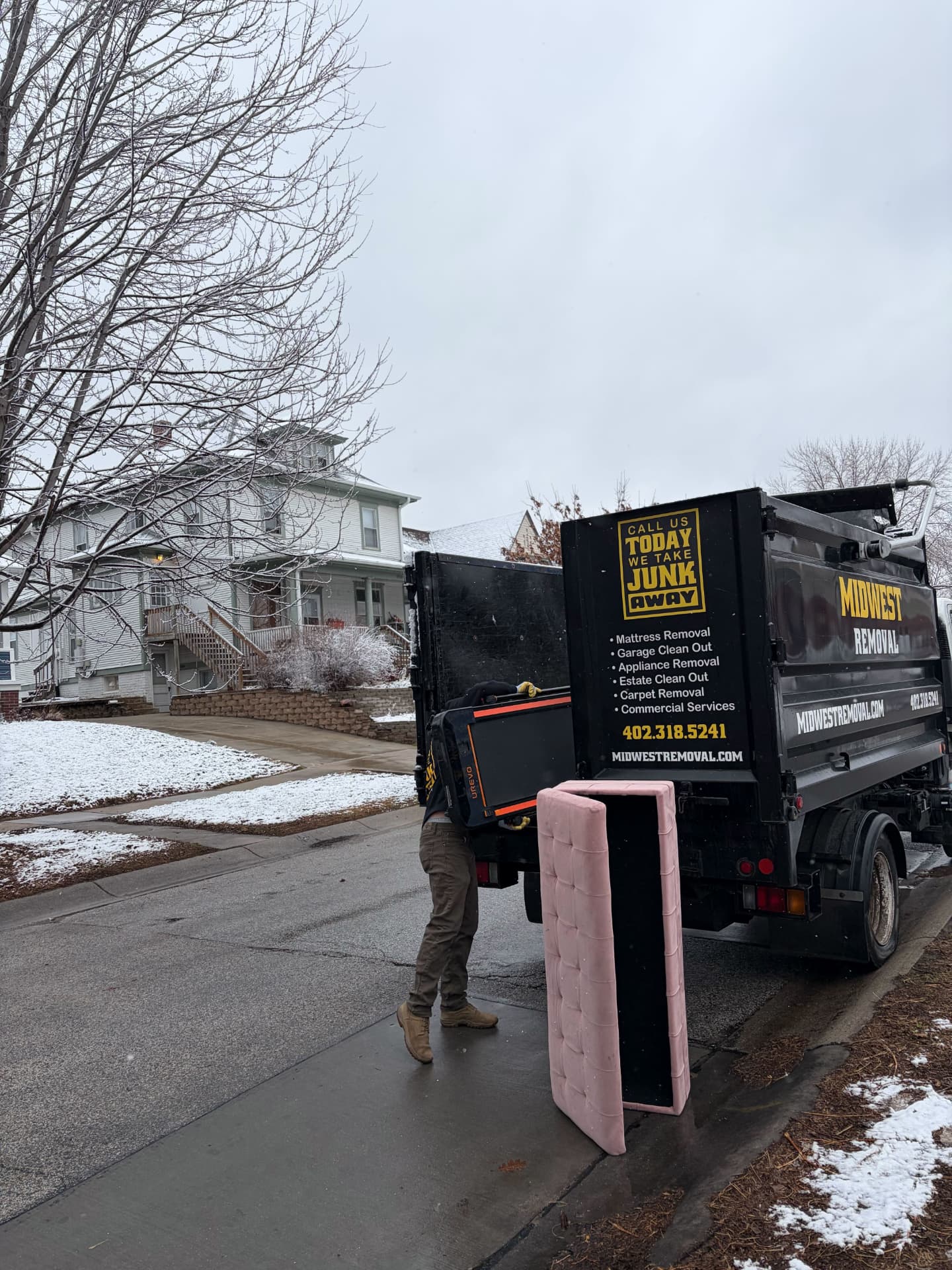 Midwest Removal crew loading a mattress into the truck on a Ralston street