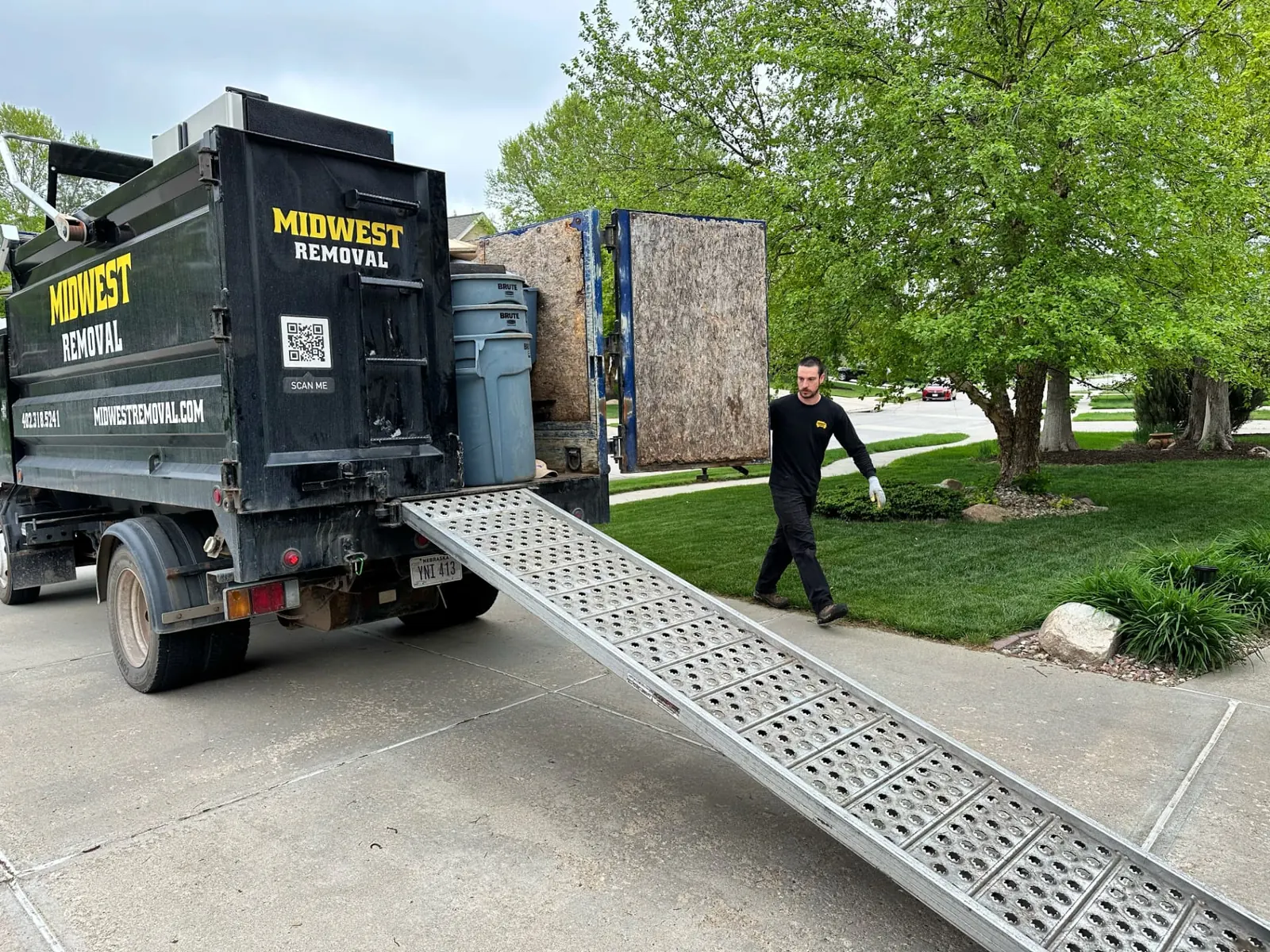 Midwest Removal crew member walking to the truck ramp during an Omaha bulk waste pickup