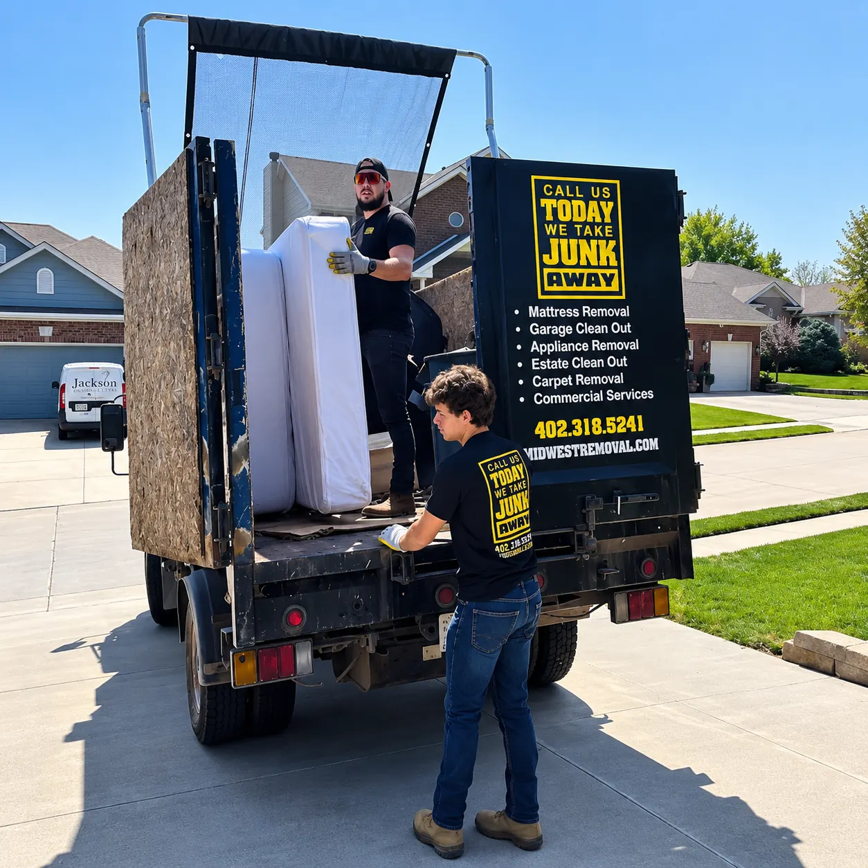 Midwest Removal crew loading a mattress into their trailer outside an Omaha home