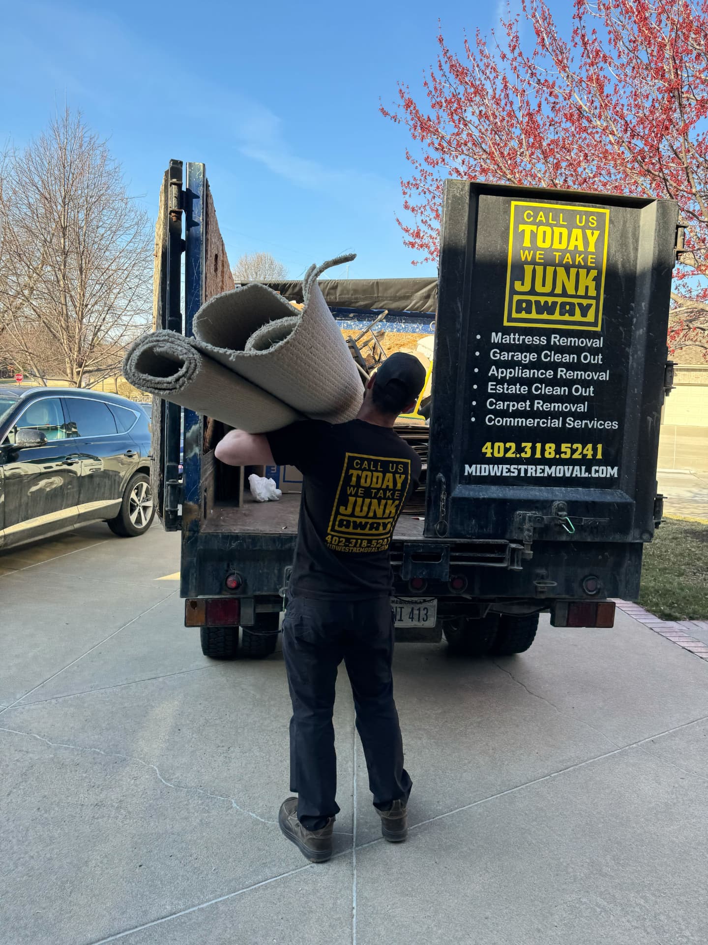 Midwest Removal crew member loading rolled carpet into the truck