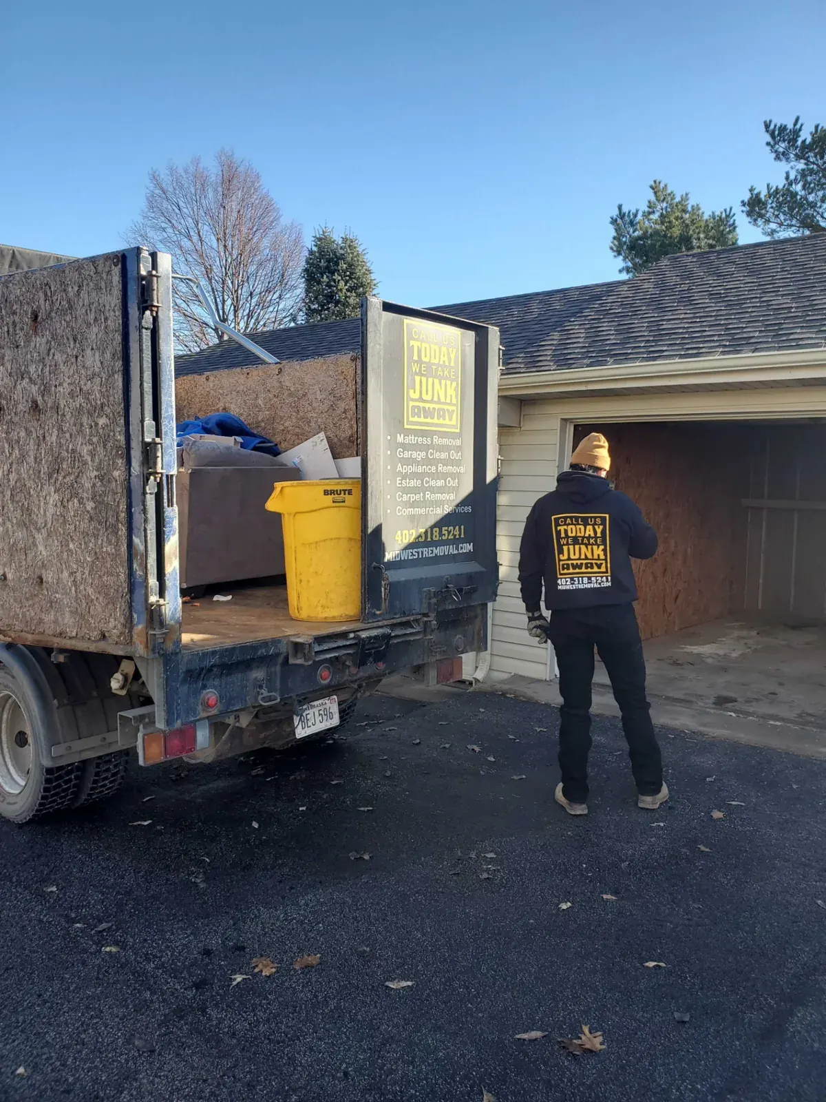 Midwest Removal crew loading garage clutter into the truck at an Omaha home