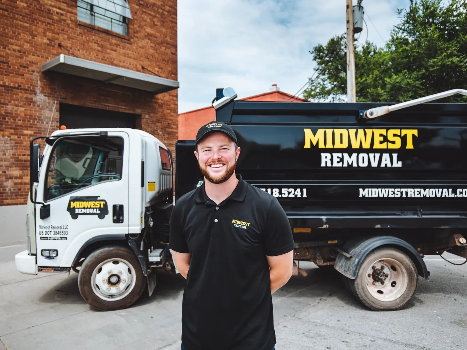 Midwest Removal team member standing between two company trucks in Omaha