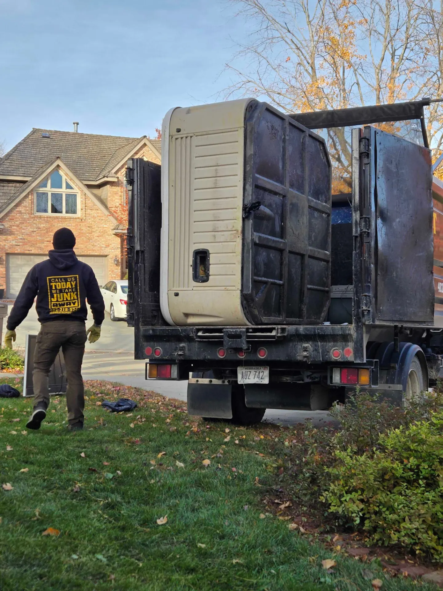 Midwest Removal crew loading an old appliance into the truck outside a home