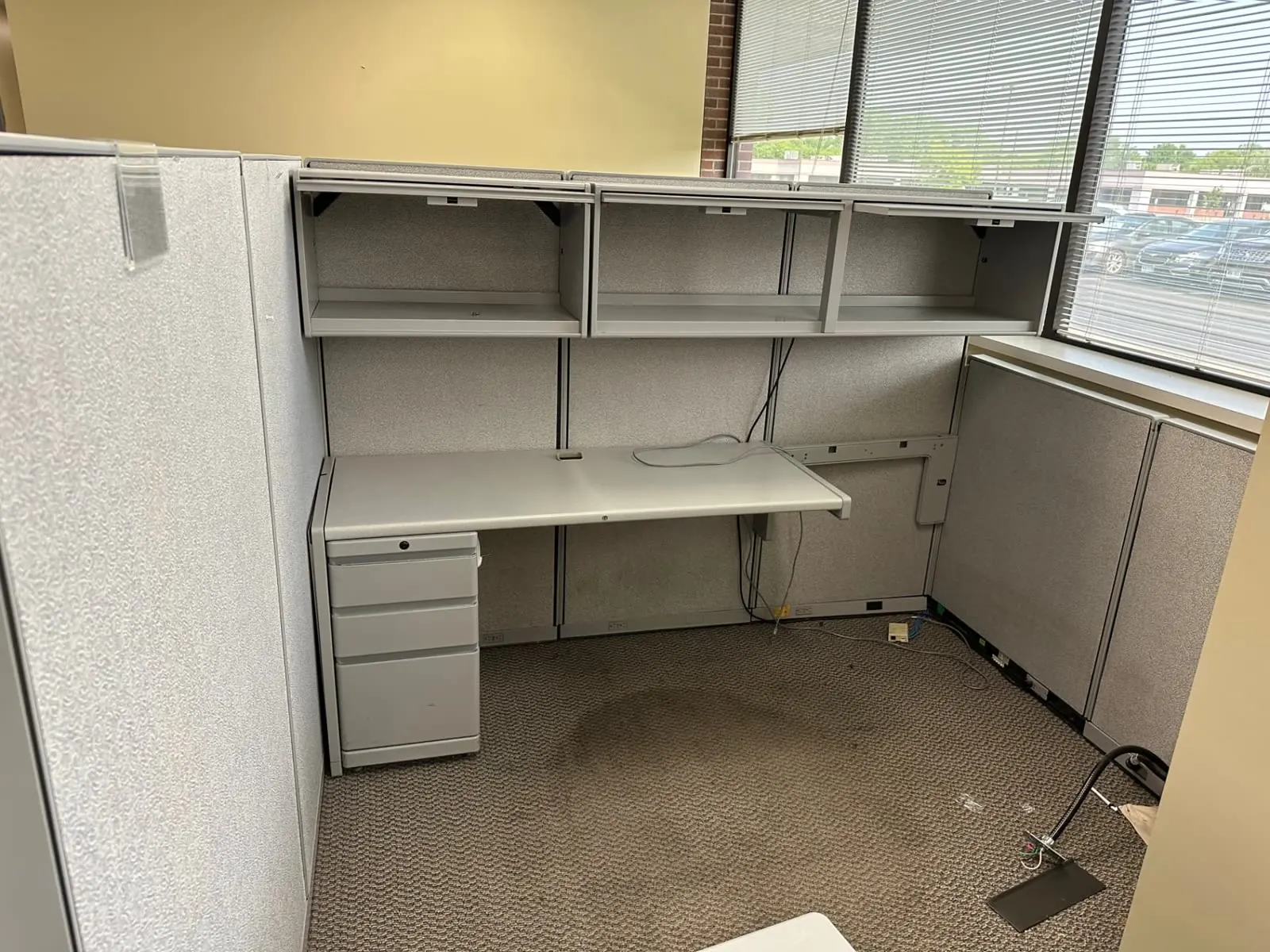Single cubicle workstation with overhead shelving being cleared