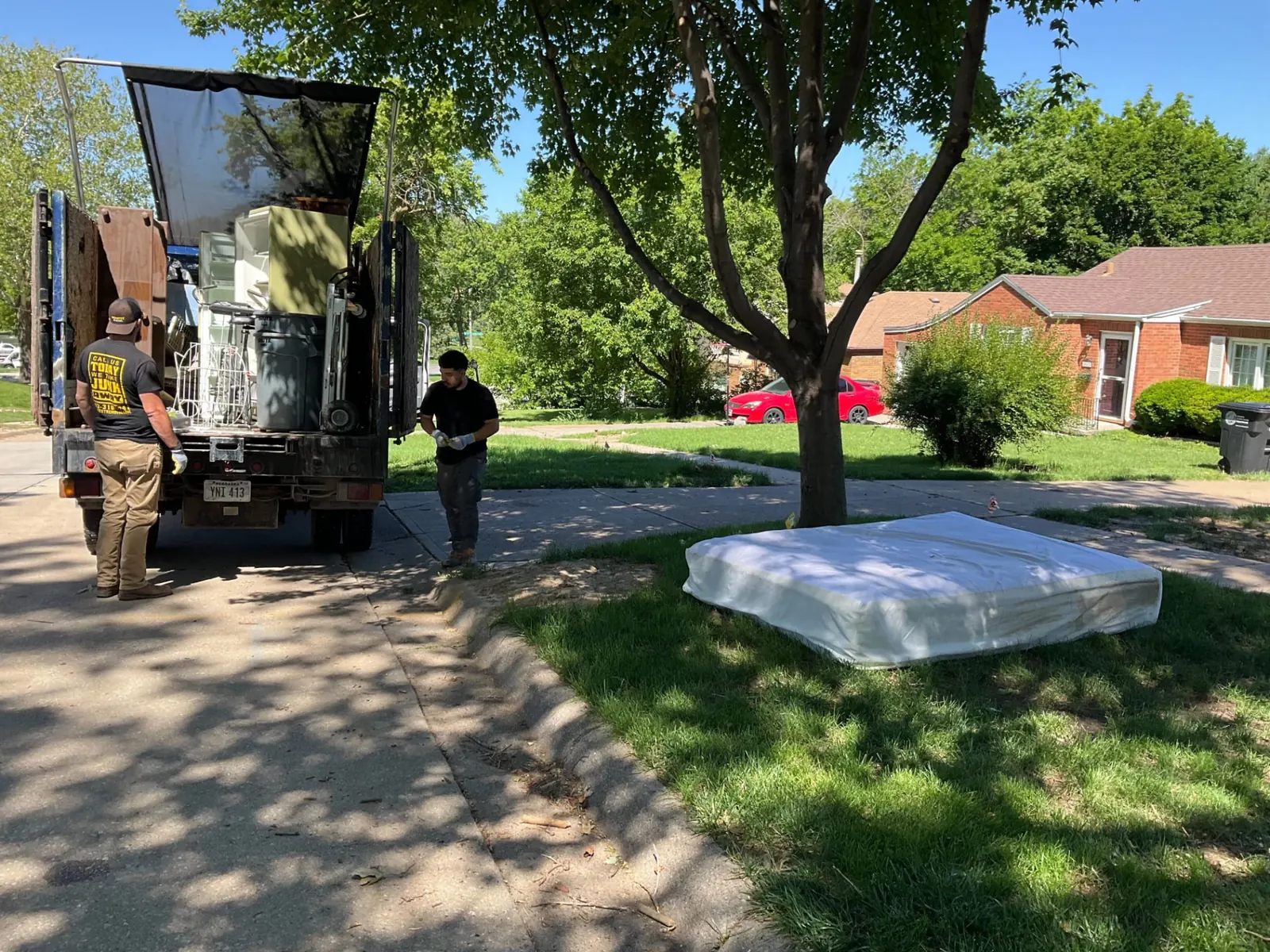 Midwest Removal crew loading a mattress from an Omaha front yard into the truck