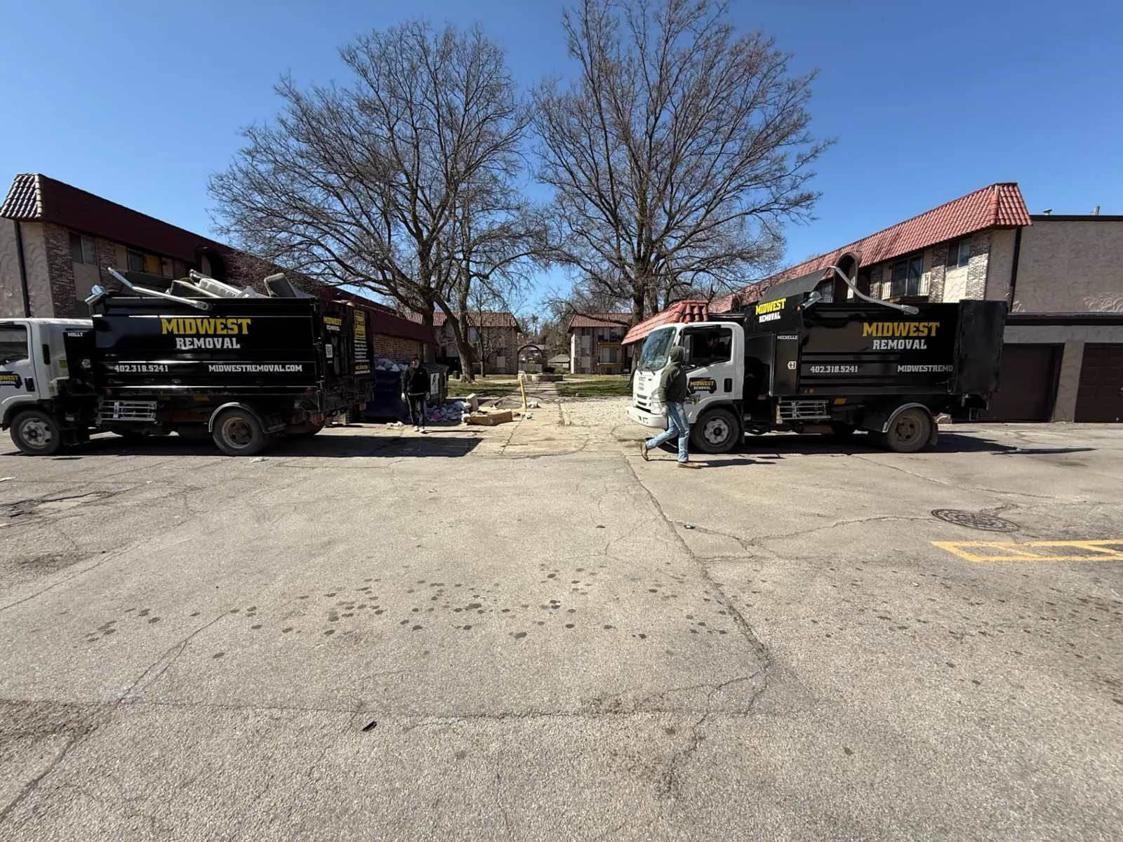 Two Midwest Removal trucks staged at an Omaha apartment complex cleanout