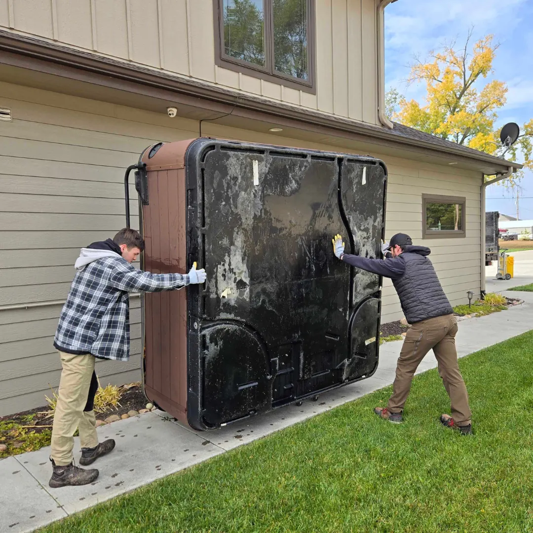 Midwest Removal crew moving an old hot tub away from a Blair home